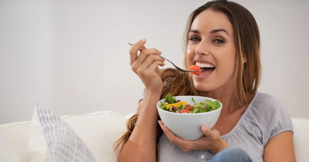 Woman smiling and eating a fresh green salad for healthy Nutrition